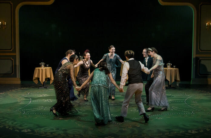 Actors: Ensemble; Props: Bistro and High Tables, Champagne Buckets, Champagne Bottles, Coupe Glasses